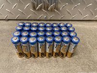 32 new GP Ultra Plus AA batteries arranged in structured rows, showing the top positive terminals and branding on the side.