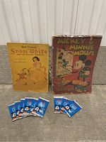 Photo showing the full collection: sealed Mickey & Minnie Mouse coloring book, Snow White and the Seven Dwarfs book, and ten sealed Mickey Mouse trading card packs on the floor.