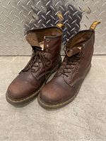 Pair of brown leather Dr. Martens boots showing top and front view with laces untied.