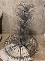 Overhead view of the chandelier showing the concentric rings of metal and tiers of crystal rods arranged like palm fronds.