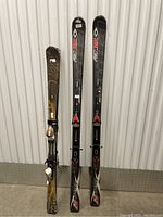 Full view of three skis shown standing up, two Limited skis and one Tierra ski with bindings