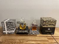Photo showing two sealed vintage Cabochard perfume bottles by Gres, each on a patterned base with matching boxes.