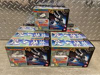 Group of nine boxed MS in Pocket V-Dash Gundam model kits arranged on floor.