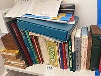 Books stacked on a shelf showing various titles including coin books, dictionaries, and physics courses.