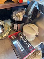Photo showing Instant Pot with instruction manuals on top, white rice cooker, and boxed Thermos container on the side.