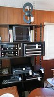 Full view of dark wood entertainment center shelf unit with multiple shelves and attached audio components, top decorative object visible.
