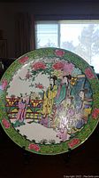 Front of first plate showing Chinese figures in garden and green floral border