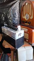 Group shot of arch-top wood radio, rectangular wood radio and silver portable transistor radio