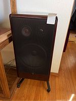 Front view of one Canton speaker upright on stand showing grille and cabinet finish