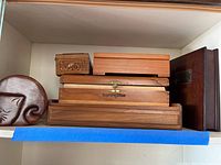 Six wooden boxes stacked, showing different sizes and a floral carved design on the small box lid.