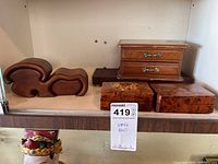 Overview photo showing all four wooden boxes on a shelf with various shapes and styles.