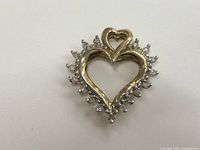 Front view of gold heart-shaped pendant with diamond border and smaller attached heart
