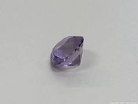 Side angle of the loose amethyst showing the depth and faceting of the stone.