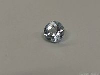 Top view showing round cut and facets of light blue aquamarine gemstone.