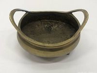 View from a low angle showing the shape, handles, and inside of the bronze bowl.