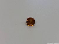 Top-down view of round faceted citrine gemstone showing color and facet detail.