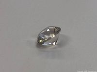 Side view of a clear round faceted gemstone showing its depth and cut angles.