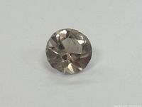 Close-up image of the round faceted gemstone showing the crown facets and overall light brown color.