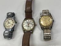 Three vintage mechanical wristwatches side by side showing front face and bands.