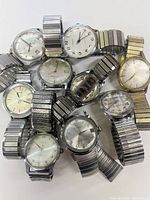 Photo showing seven vintage mechanical wristwatches from brands Sebon, Telix, Cardinal, Elbon, laid out with metal stretch bands visible.