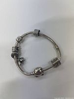 Silver Pandora bracelet with 5 charms laid flat on a white surface showing general appearance and condition.