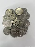 Pile of Canadian silver dollars and half dollars showing obverse and reverse sides including portraits of Queen Elizabeth II and various crests and commemorative designs