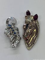 View of both brooches side by side showing designs and colors.