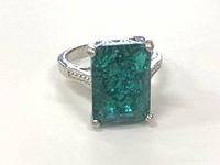 Front view of rectangular green gemstone set in sterling silver ring with four prongs.