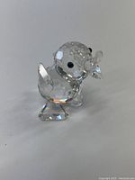 Front and side view of the Swarovski crystal duck figurine showing faceted crystal body, black eyes, and clear detailed beak and wings.