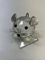 Clear image of Swarovski crystal mouse figurine from front showing faceted crystal body, metal ears, black eyes and nose, metal whiskers, and clear crystal base.