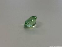 Green marquise cut uranium glass gemstone photographed on a light background.