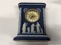 Front view of the blue jasperware Wedgwood mantel clock showing classical white relief figures and the clock face with gold-tone bezel.
