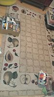 Full view of food themed area rug with fruit designs around border and grid pattern center, shows overall condition and size in room context.