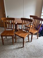 Four wooden dining chairs grouped around a dining table, showing overall condition and style.