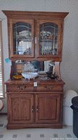 Full view of oak hutch showing upper glass doors, two drawers, and lower cupboard doors.