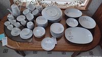 Full set of 68 fine china pieces displayed on table showing cups, plates in various sizes, bowls, creamers, sugar bowls.