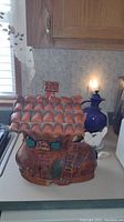 Large ceramic shoe-shaped cookie jar by itself showing roof and front door detail