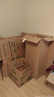 Corner stack of U-Haul medium moving boxes, some assembled and others flat-packed.