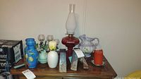 Full view of wooden table displaying all items including oil lamp, various vases, petrified wood bookends, candles, candleholders and decorative items.