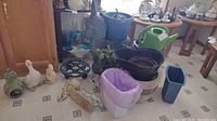 Full view of all items in the lot including planters, watering cans, coal bucket, and yard art