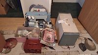 Full lot showing sewing machine set up on floor with carrying case behind and sewing boxes and basket in front