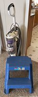Shark Navigator Professional vacuum with hose and additional attachments, placed near a step stool for scale.