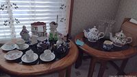 Wide view of table with various ceramic teapots, cups, figurines and kitchen items