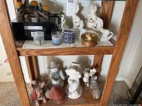 Two shelves of assorted ceramic animal figurines, white unicorns, deer, a rabbit, and small statues, alongside several candles and a solar turtle lamp on upper shelf.