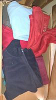 Photo of assorted folded sweatshirts and jackets in colors black, red, blue, and grey