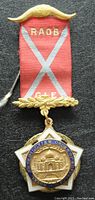Front view of the 1931 India Freemason jewel medal showing red ribbon with RAOB and GLE lettering, gold-tone top and bottom, and the central pendant with an Eastern Order of Rainbow for Girls emblem.