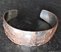 Front view of the silver and copper cuff bracelet showing the engraved dragonfly design on the outer band.