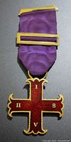 Front view of the Freemason type jewel cross medal showing red enamel, gold trim, and letters H, S, V, I on the cross arms attached to purple ribbon with gold bars.