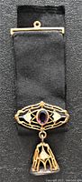 Front of the Freemason gold filled medal with visible amethyst gemstone set within intricate gold filigree and attached to black ribbon.