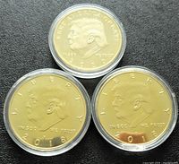 Front side of three gold plated Trump tokens showing left-profile portrait of Donald Trump with year and inscriptions.